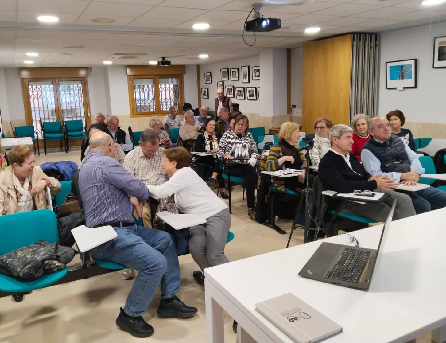 Socios del proyecto Josefina Castro Senior Cohousing sentados en un aula, charlando unos con otros.