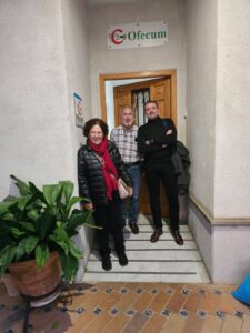 La imagen muestra a tres personas de pie en la entrada de un edificio con un letrero de "Ofecum" sobre la puerta.: José Carlos Rodrigo, de Hábitat Colaborativo, y dos socios del proyecto residencial Josefina Castro Senior Cohousing